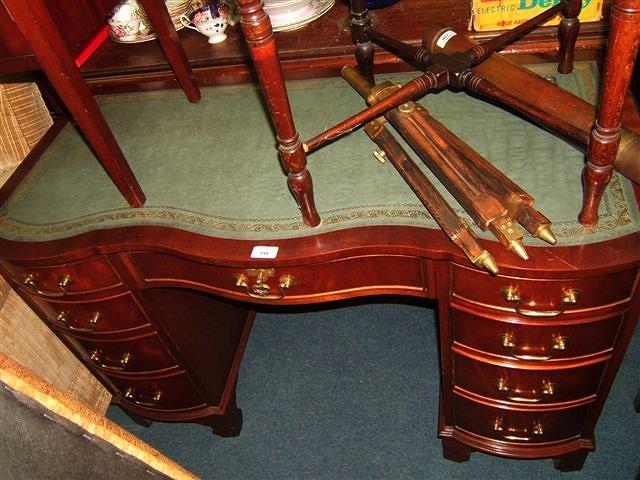 Appraisal: A reproduction mahogany kneehole desk with leather inset top by