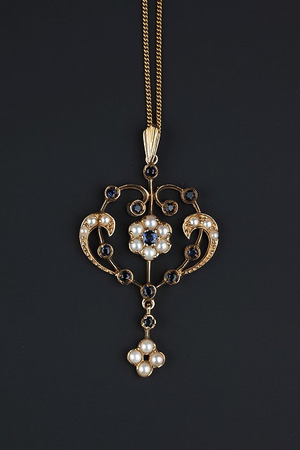 Appraisal: A SAPPHIRE AND CULTURED PEARL PENDANT the scrolled openwork cartouche