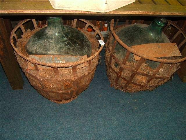 Appraisal: Two green glass carboys in straw padded wrought iron cages