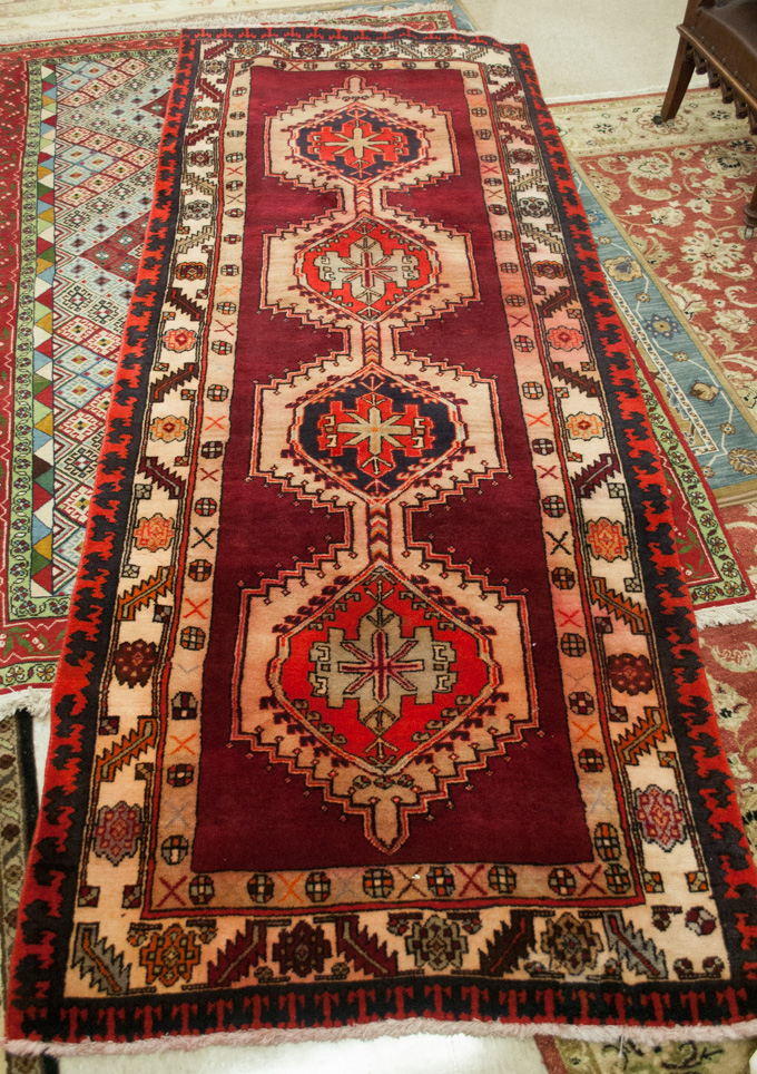 Appraisal: PERSIAN TRIBAL HALL CARPET featuring four geometric pole medallions on