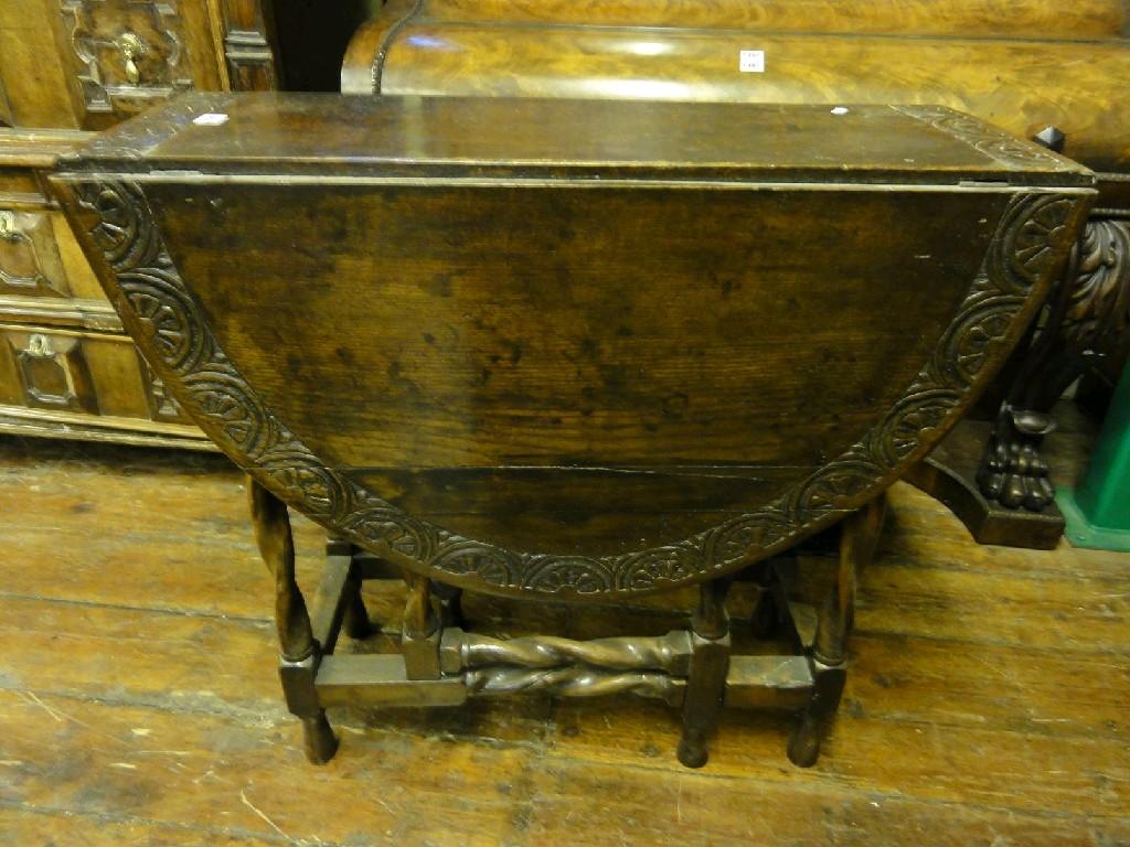 Appraisal: An antique oak oval drop leaf gate leg table with