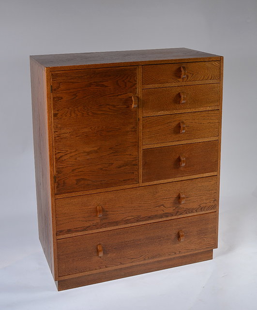 Appraisal: A Cotswold School oak tallboycirca having a single cupboard flanked