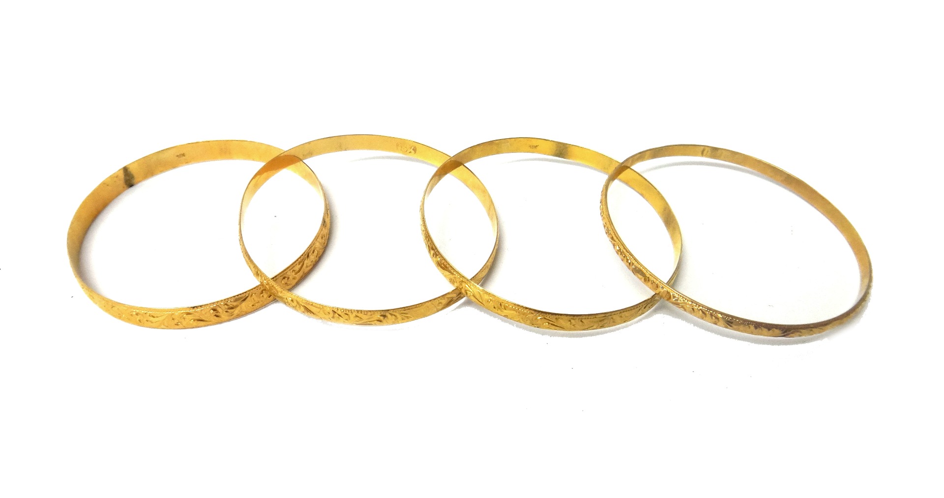 Appraisal: Four circular gold bangles each with scroll engraved decoration mostly