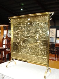 Appraisal: A brass fire screen depicting a chariot race