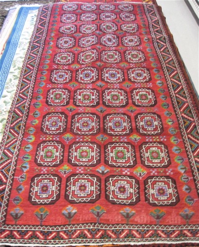 Appraisal: PERSIAN TURKOMAN CARPET repeating geometric medallion design on plain red