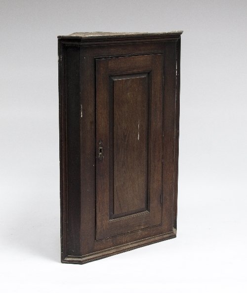 Appraisal: An oak hanging corner cupboard with panelled door cm high