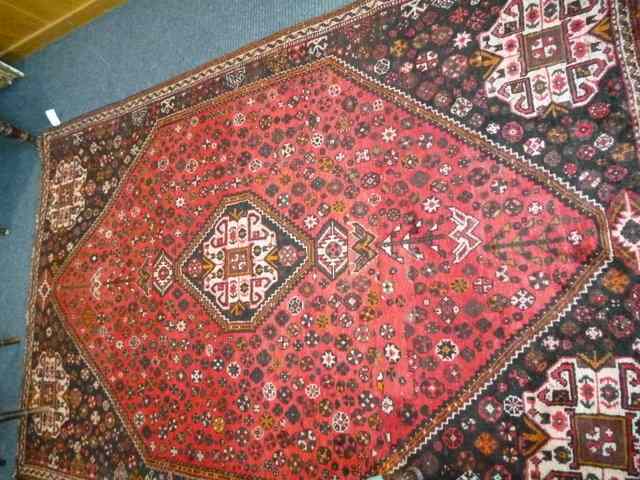 Appraisal: A WINE GROUND RUG with stylised floral designs to the