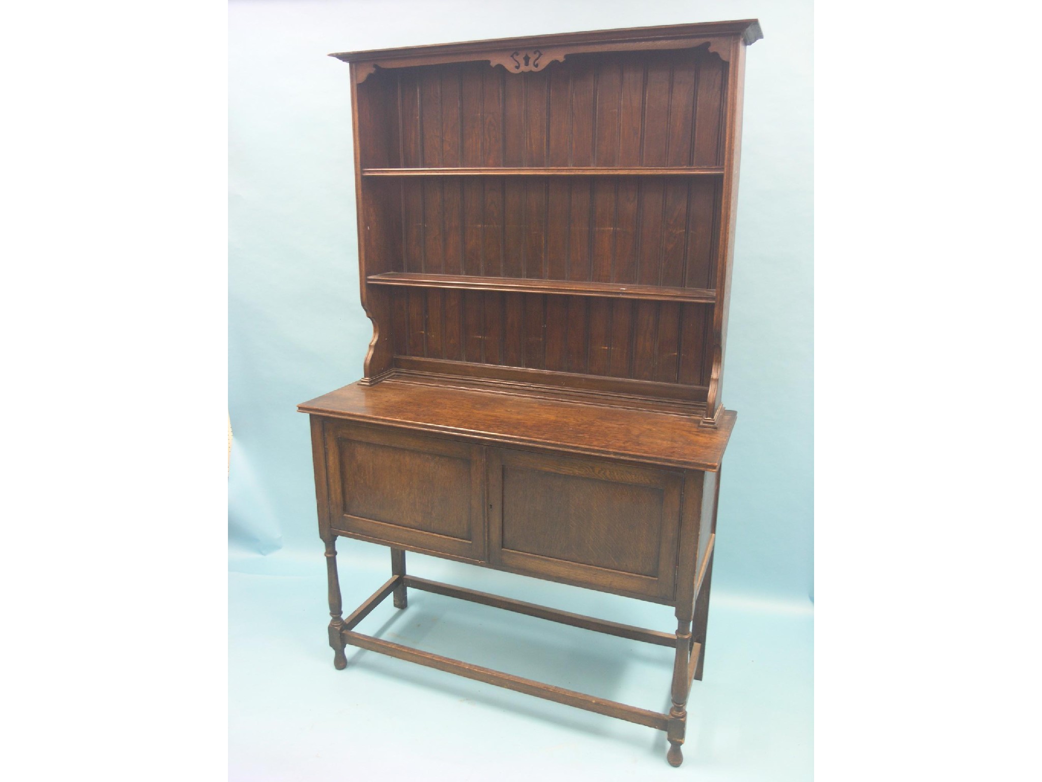 Appraisal: A solid dark oak dresser twin-shelf plate rack above panelled