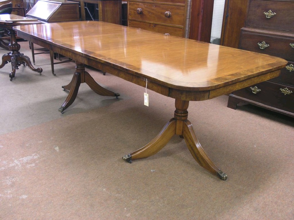 Appraisal: A reproduction walnut twin pillar dining table with extra leaf