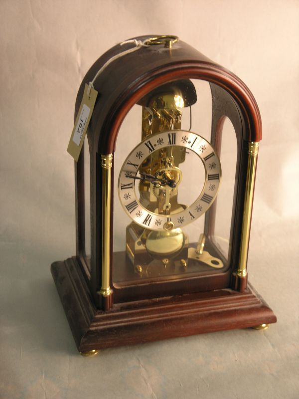 Appraisal: A reproduction mantel clock with skeleton movement in domed mahogany