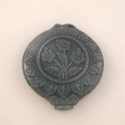 Appraisal: A circular section of grey green jade with foliate carved