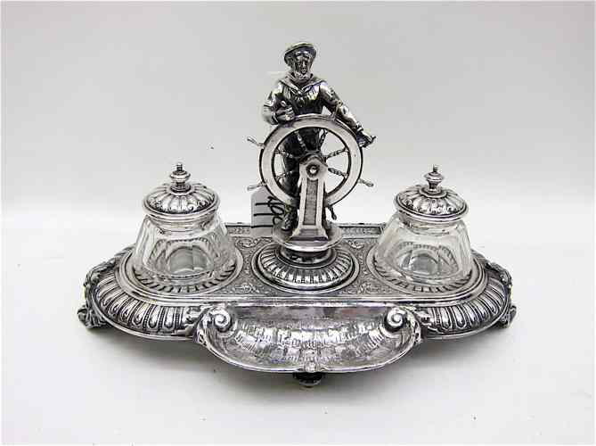 Appraisal: VICTORIAN SILVERPLATED FIGURAL INKWELL a sailor and ship's wheel flanked