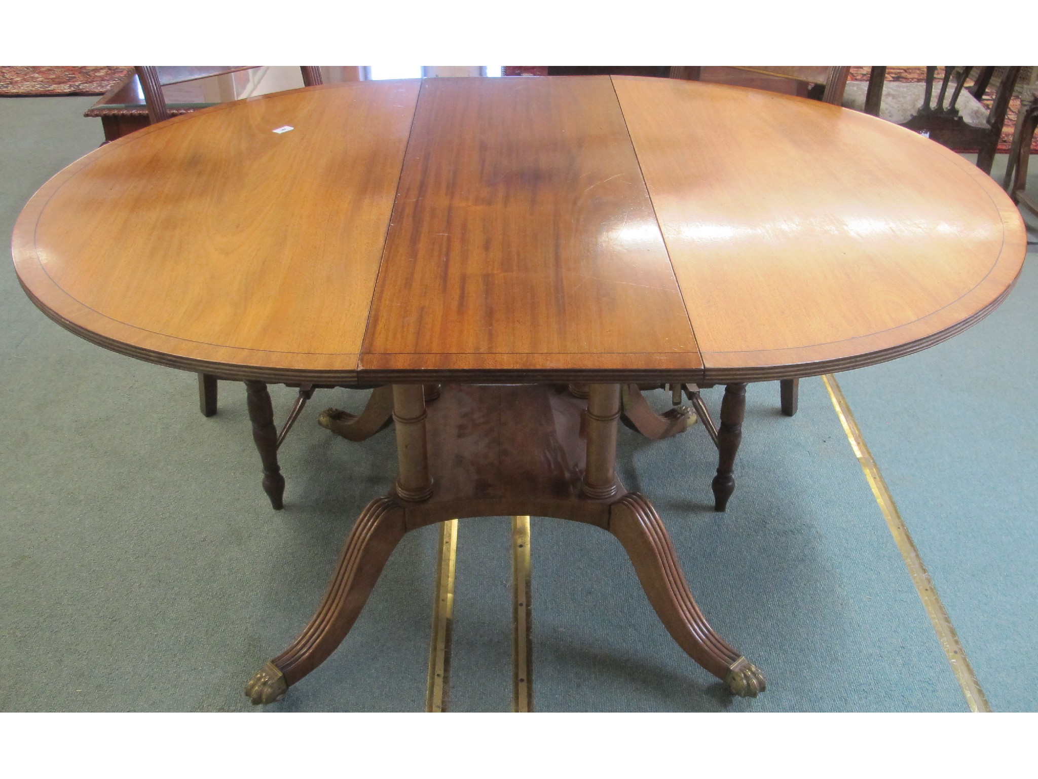 Appraisal: A mahogany extending circular table with brass paw feet