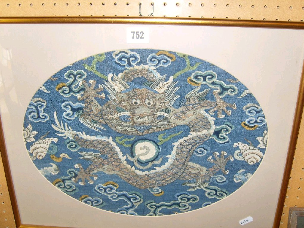 Appraisal: An oriental blue ground fabric panel of oval form with