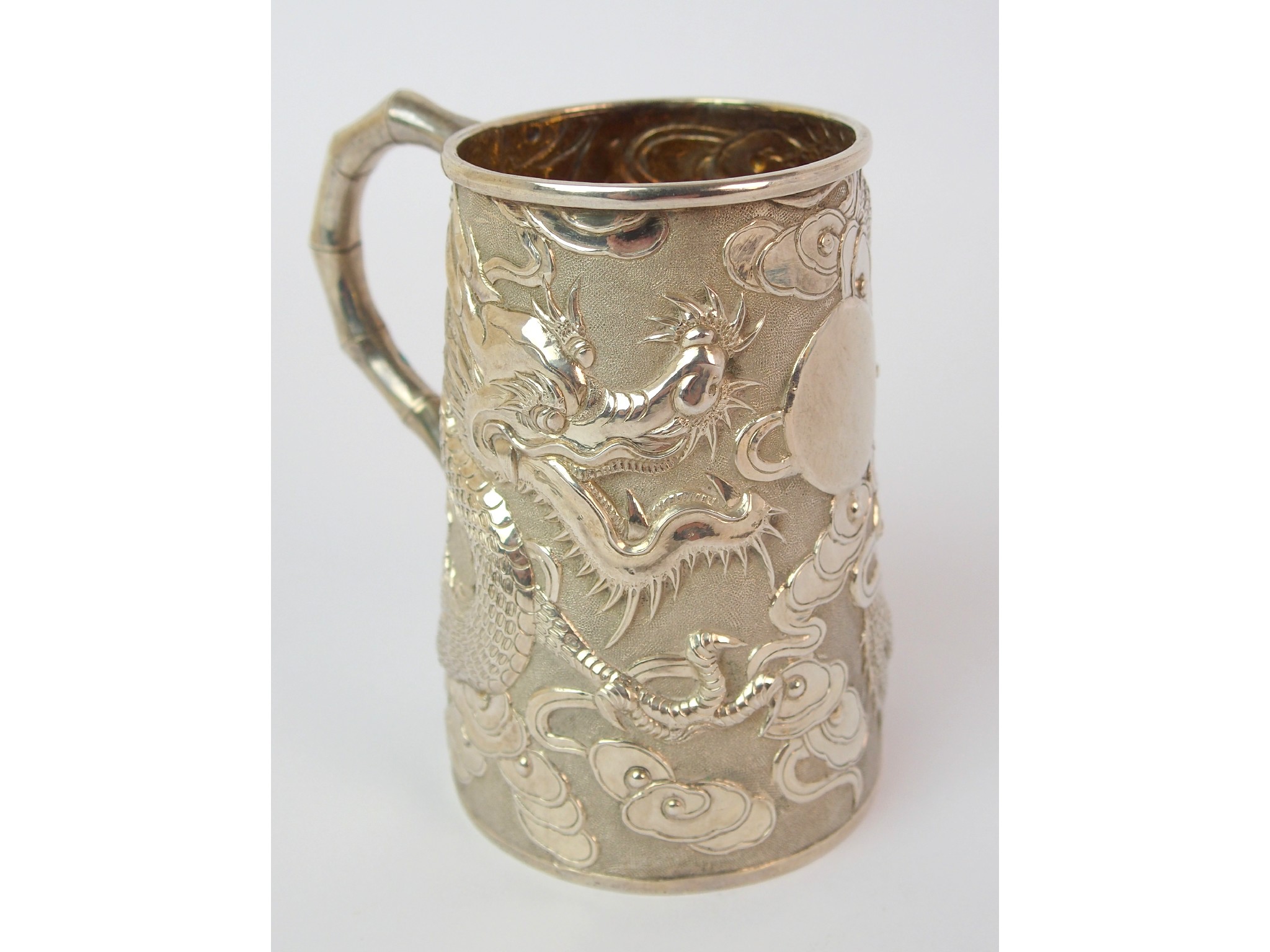 Appraisal: A Chinese silver small cylindrical drinking vesseldecorated with dragons chasing