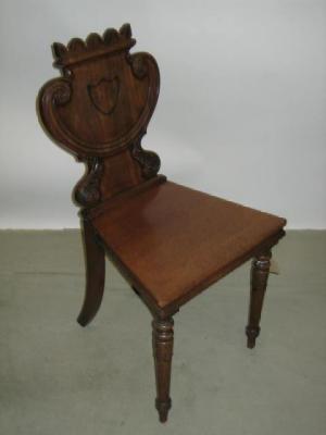 Appraisal: A MAHOGANY HALL CHAIR the scrolled shield back carved with