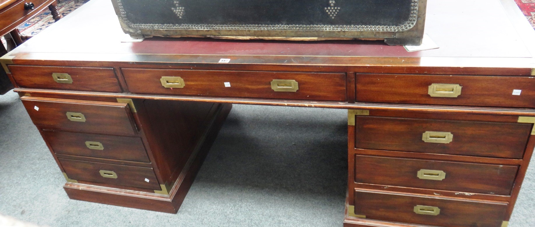 Appraisal: A campaign style brass bound mahogany pedestal desk with nine