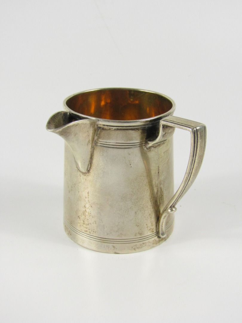 Appraisal: A thC white metal tapered cylindrical jug with reeded borders