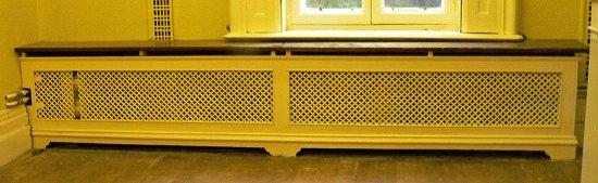 Appraisal: A double pierced cast radiator surround with wooden top on