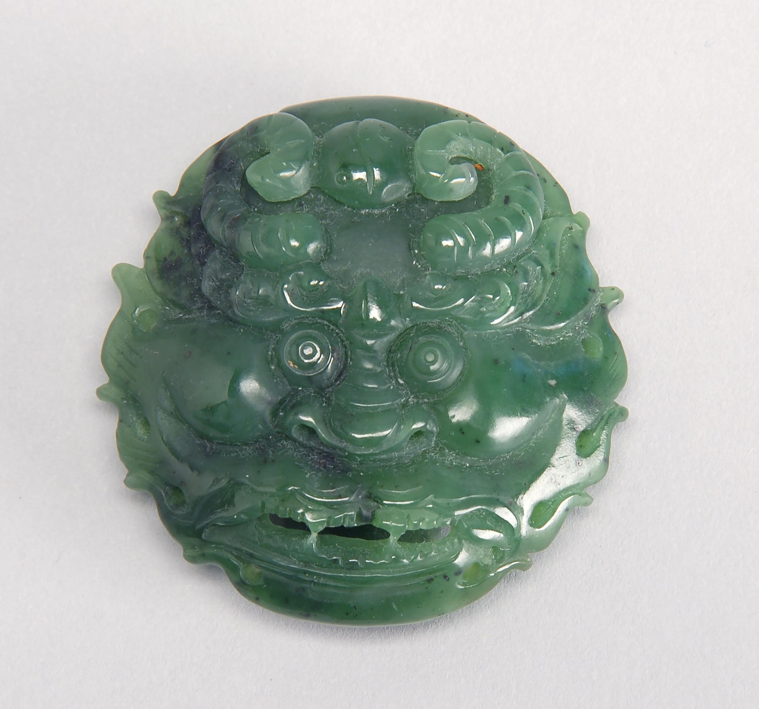 Appraisal: GREEN JADE BELT SLIDE th CenturyIn demon-mask design Length cm