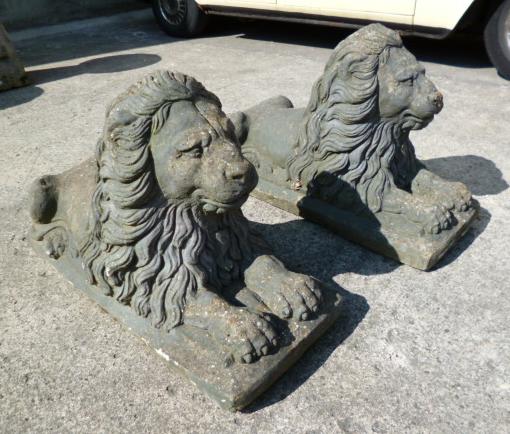 Appraisal: A PAIR OF COMPOSITION STONE LIONS modelled recumbent raised on