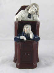 Appraisal: A ceramic group of a preacher or judge and his