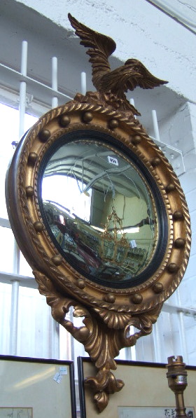 Appraisal: A Regency gilt framed convex wall mirror with eagle surmount