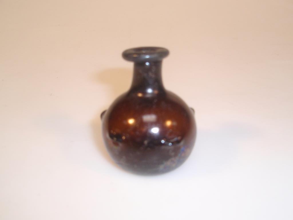 Appraisal: A small post-Roman bottle made in purple-brown glass the bulbous