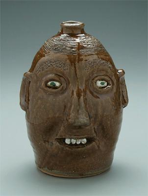 Appraisal: Reggie Meaders face jug runny brown glaze ceramic teeth green