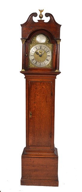 Appraisal: AN OAK HOUR LONGCASE CLOCK the arched brass dial with