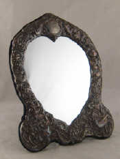 Appraisal: An ornately embossed silver heart shaped table mirror with strut