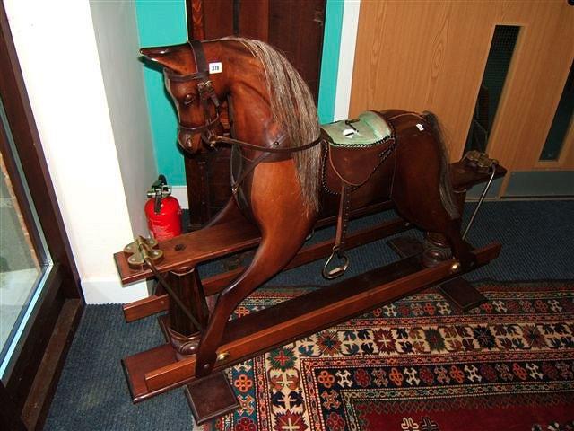 Appraisal: A carved hardwood rocking horse with leather saddle on a