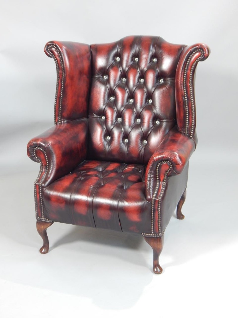 Appraisal: A red vintage style leather wingback chair with a button