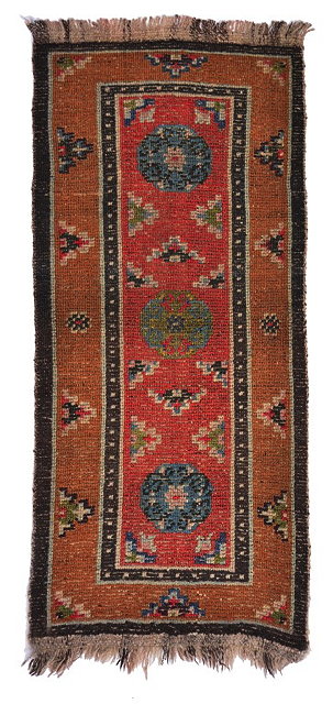 Appraisal: A SMALL TIBETAN KNOTTED WOOL PILE RUG with central red