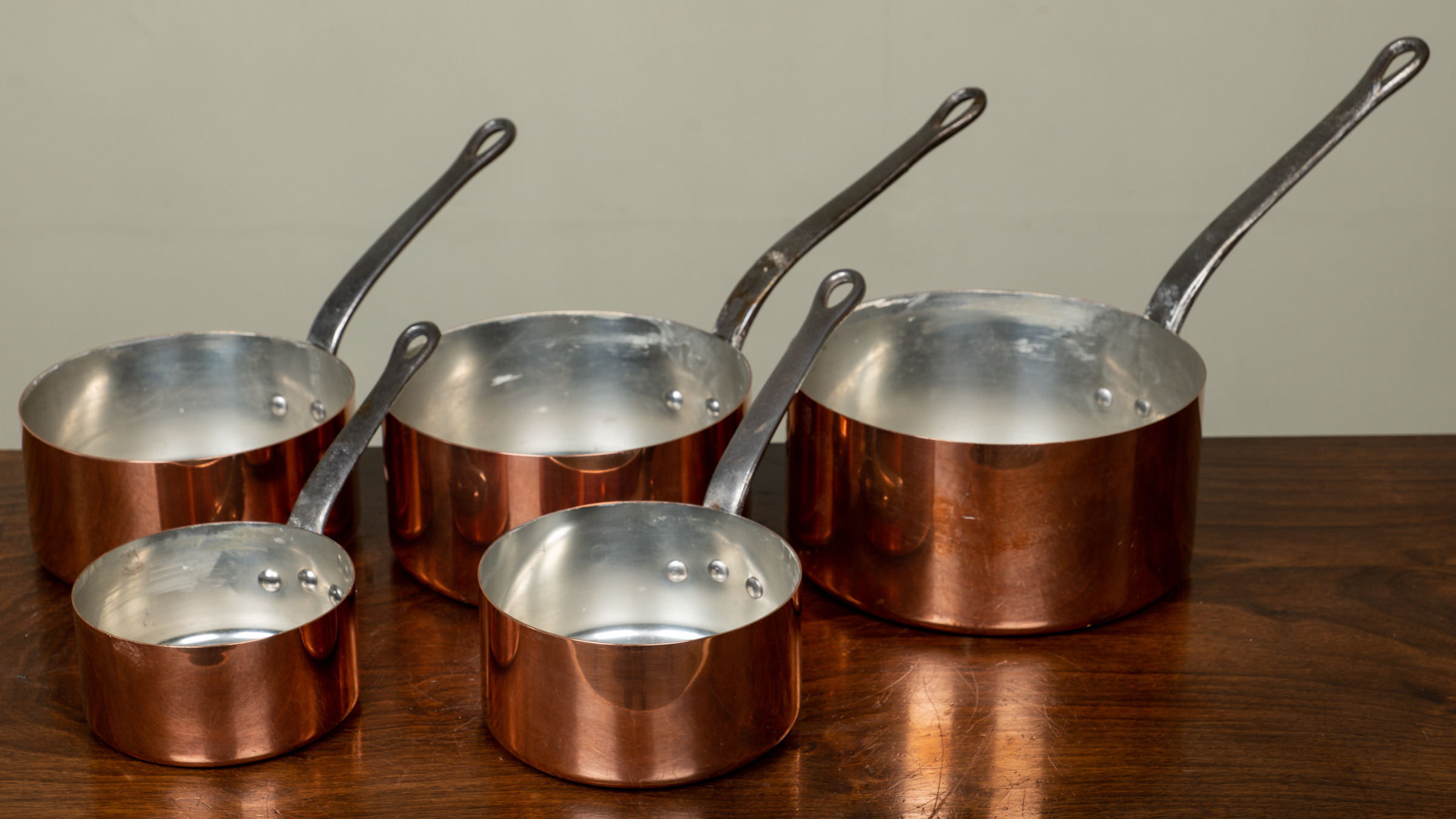 Appraisal: A set of five graduated copper saucepans with tin lining