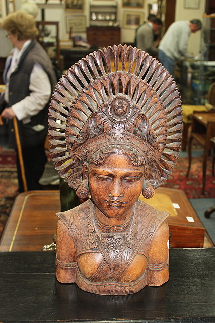 Appraisal: AN INDONESIAN HARDWOOD CARVING OF A WOMAN WITH LARGE HEADDRESS