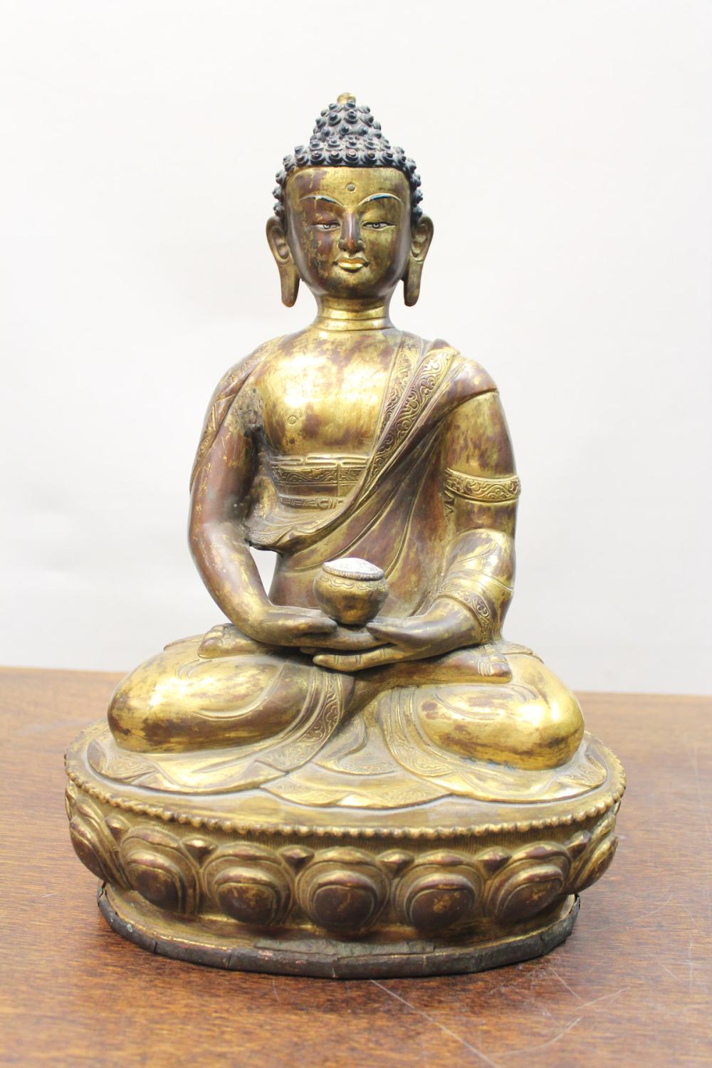 Appraisal: CHINESE GILT BRONZE BUDDHA SCULPTURE depicting a seated Buddha holding