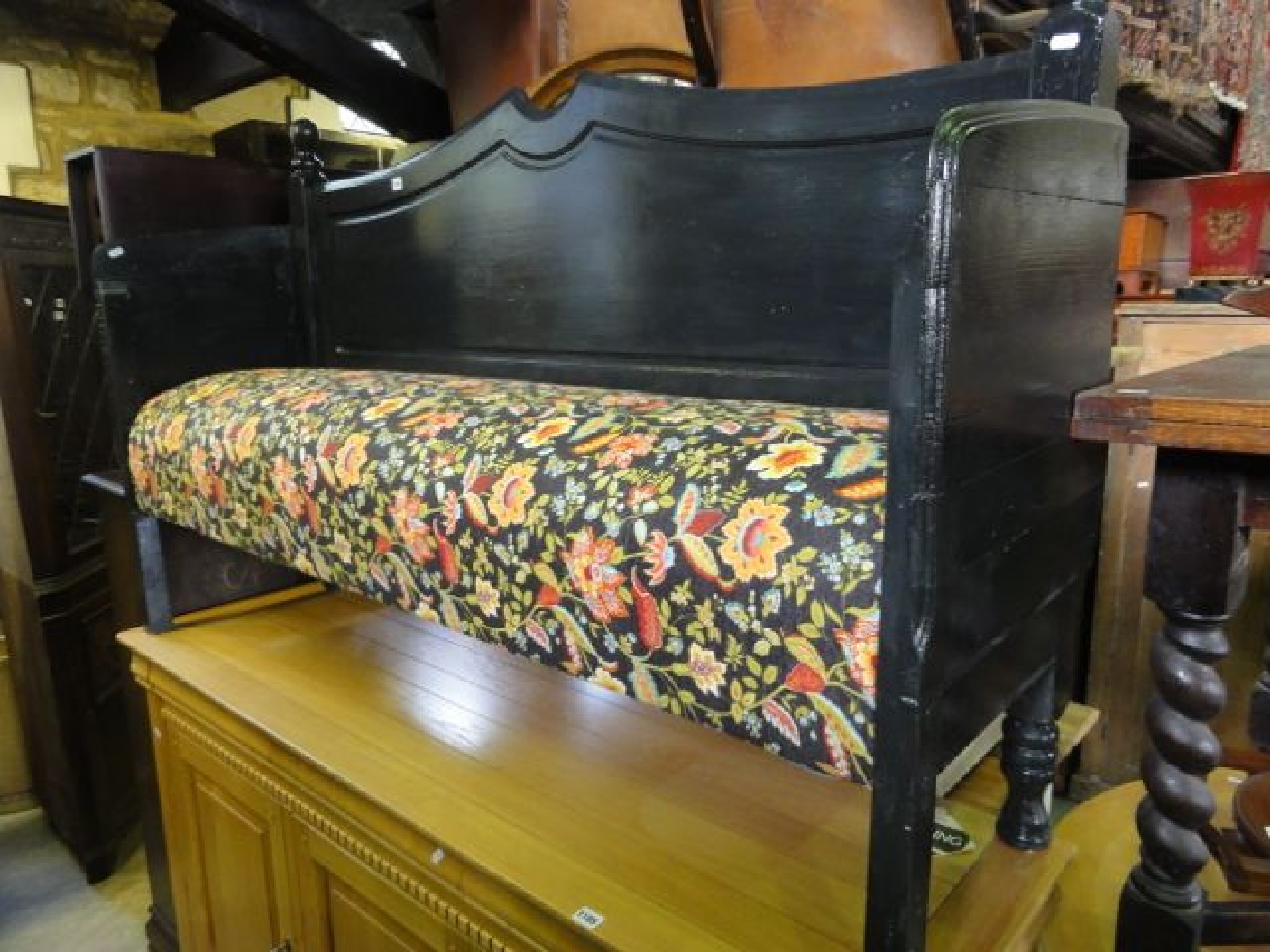 Appraisal: An ebonised bench with floral patterned upholstered seat beneath a