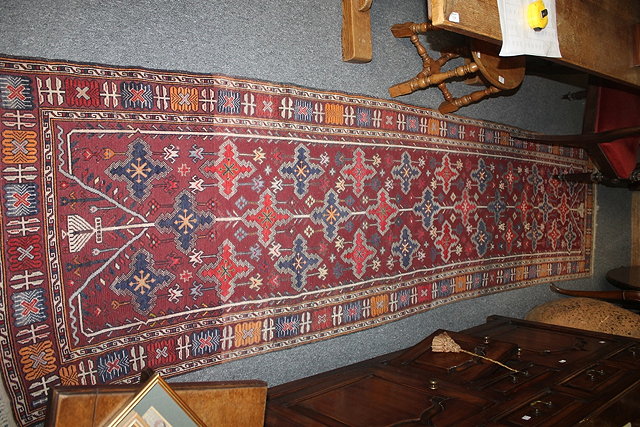 Appraisal: AN EASTERN WOOL RUNNER of dark red ground with running