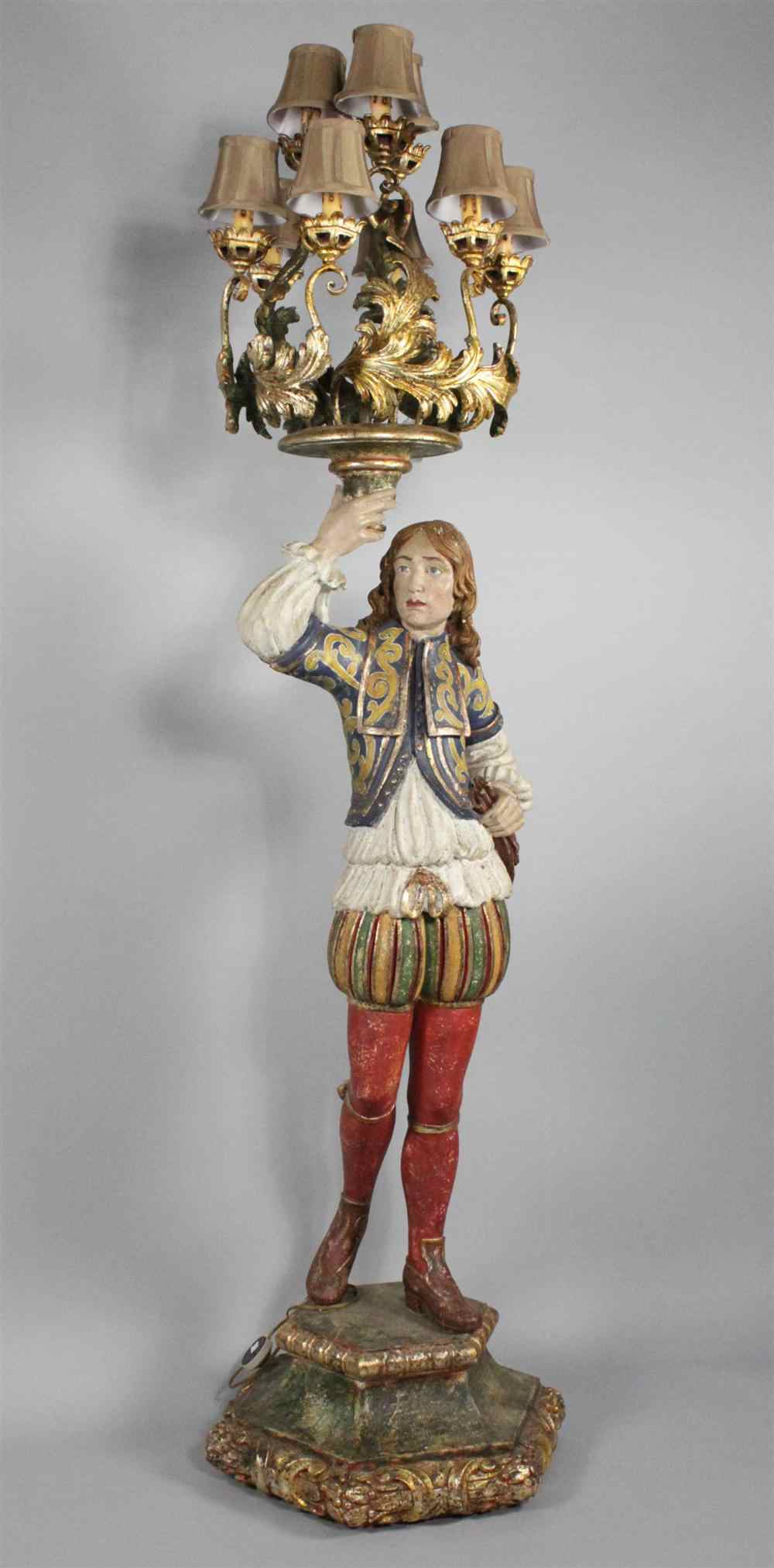 Appraisal: CONTINENTAL POLYCHROME PAINTED AND CARVED FIGURE OF A COURTIER CANDELABRA