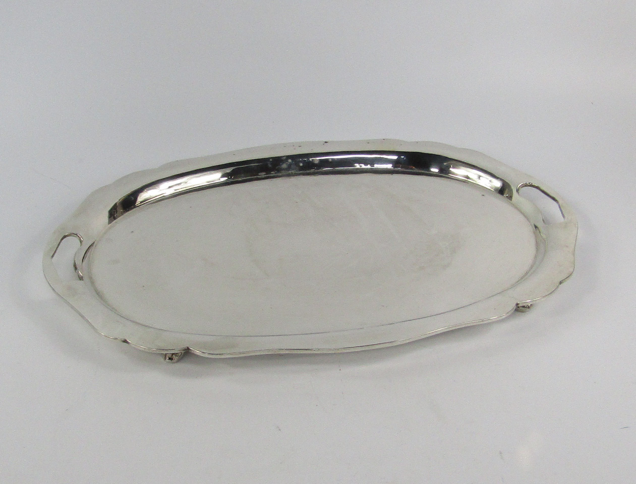 Appraisal: A twin handled and white metal tray with a shaped