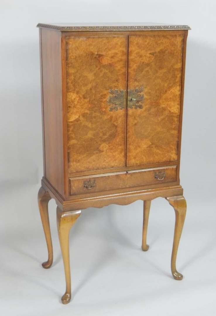 Appraisal: A reproduction walnut cocktail cabinet the top with a carved