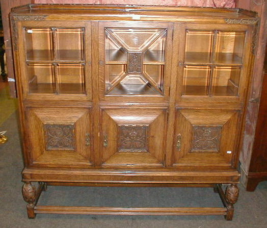 Appraisal: A carved oak display cabinet with bevelled glazed doors and