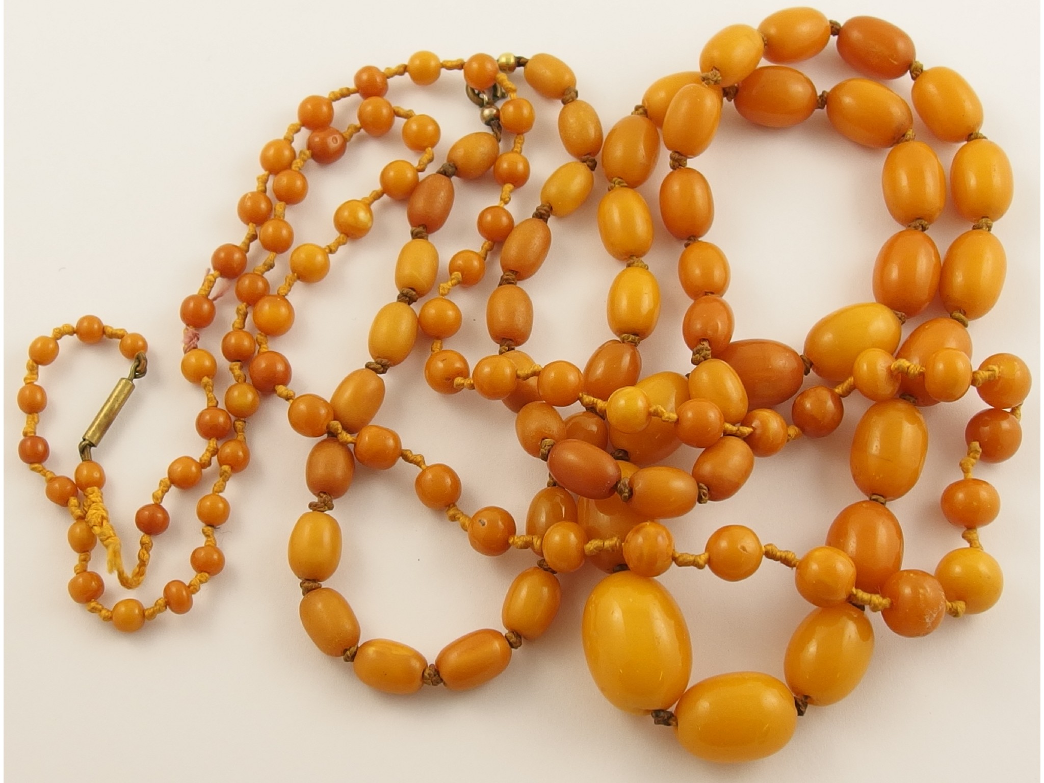 Appraisal: Two strings of yellow amber coloured beadsthe oval beads weigh