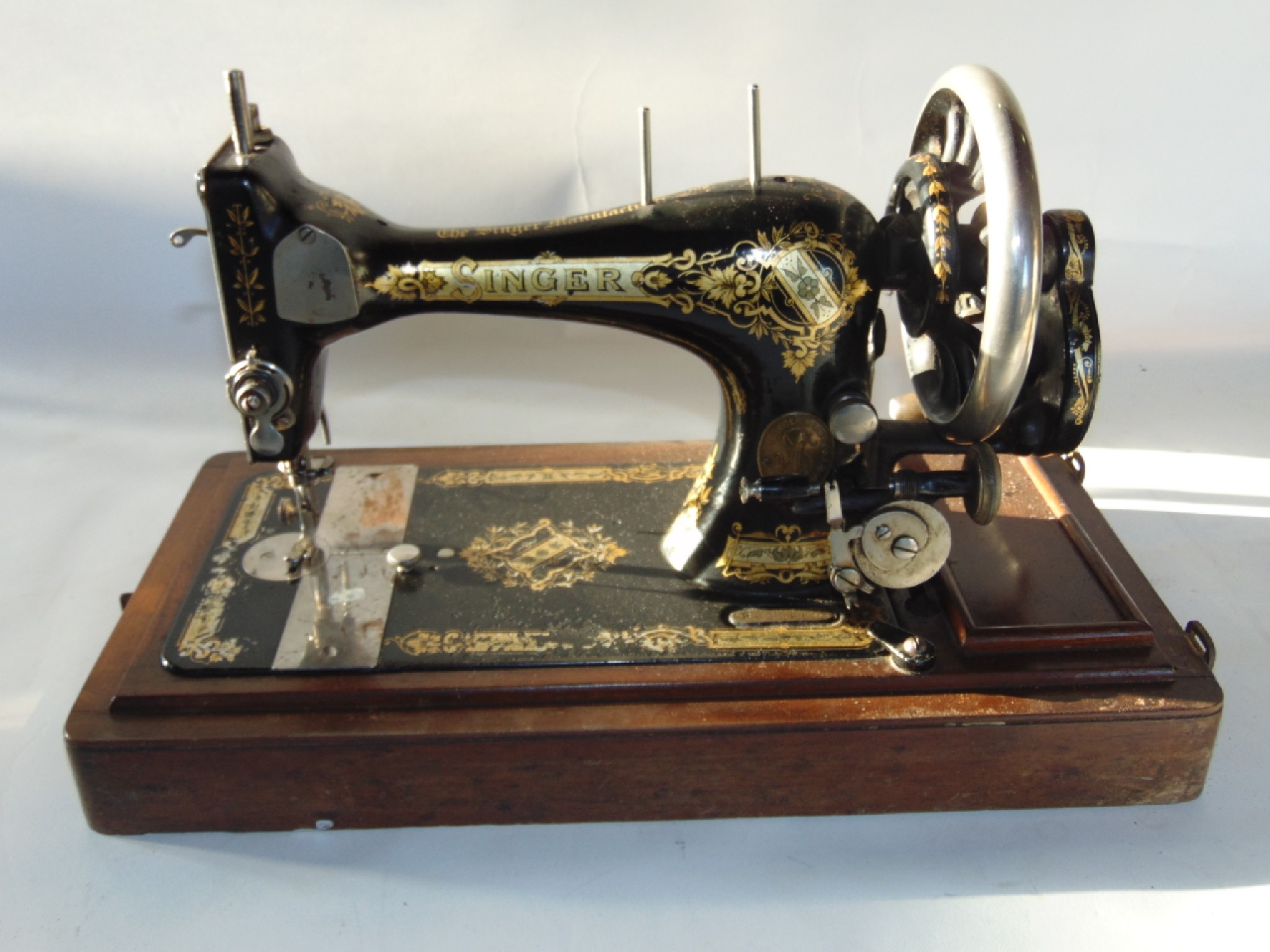 Appraisal: An antique Singer sewing machine raised on a stepped timber