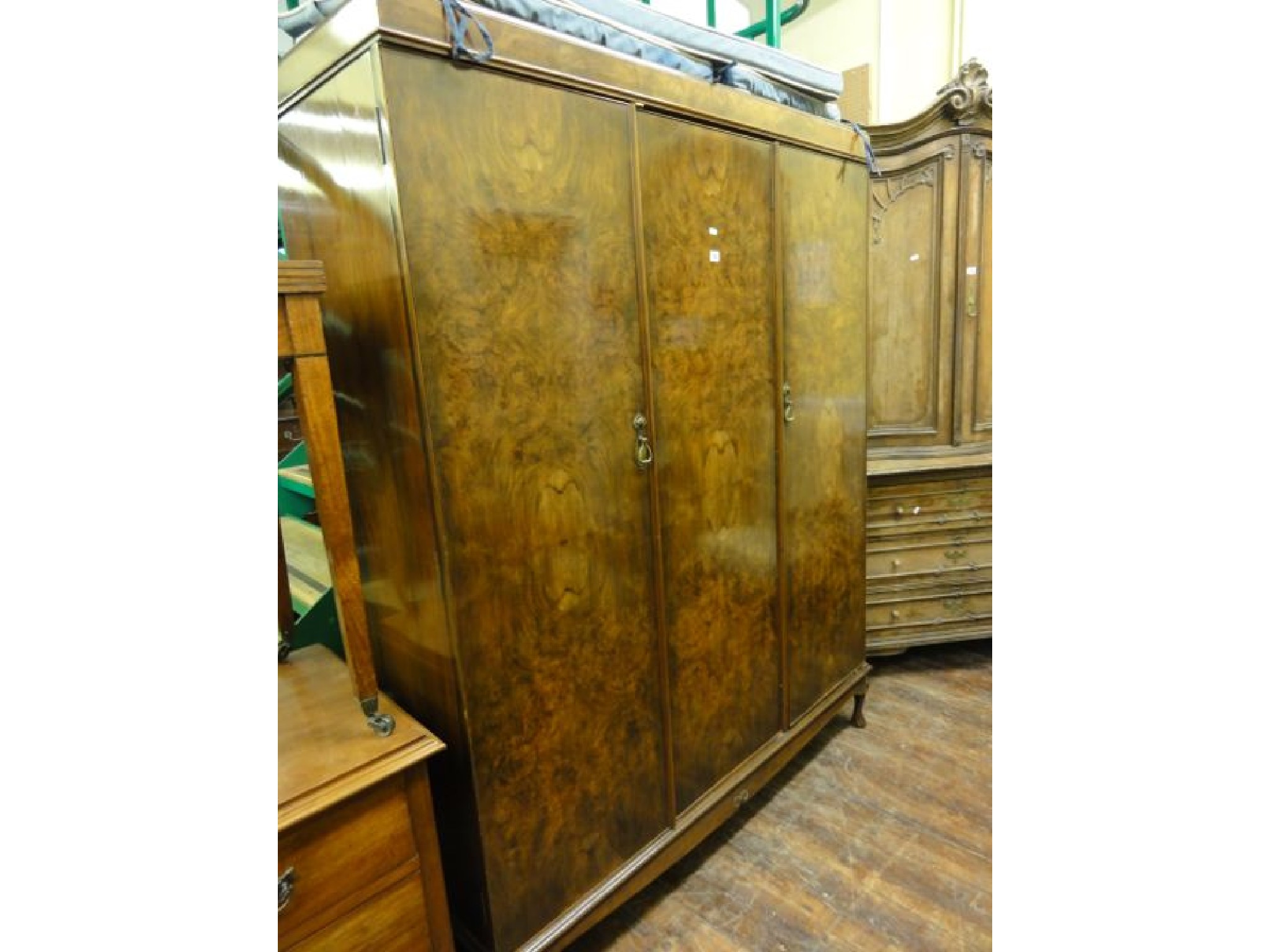 Appraisal: A figured walnut veneered triple wardrobe enclosed by three panelled