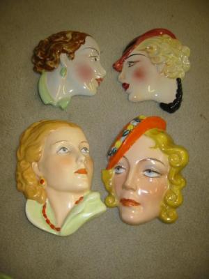 Appraisal: FOUR ART DECO POTTERY WALL MASKS modelled as ladies faces