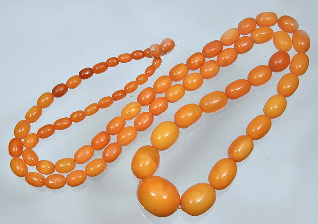 Appraisal: A GRADUATED OVAL AMBER BEAD NECKLACE egg yolk colour long