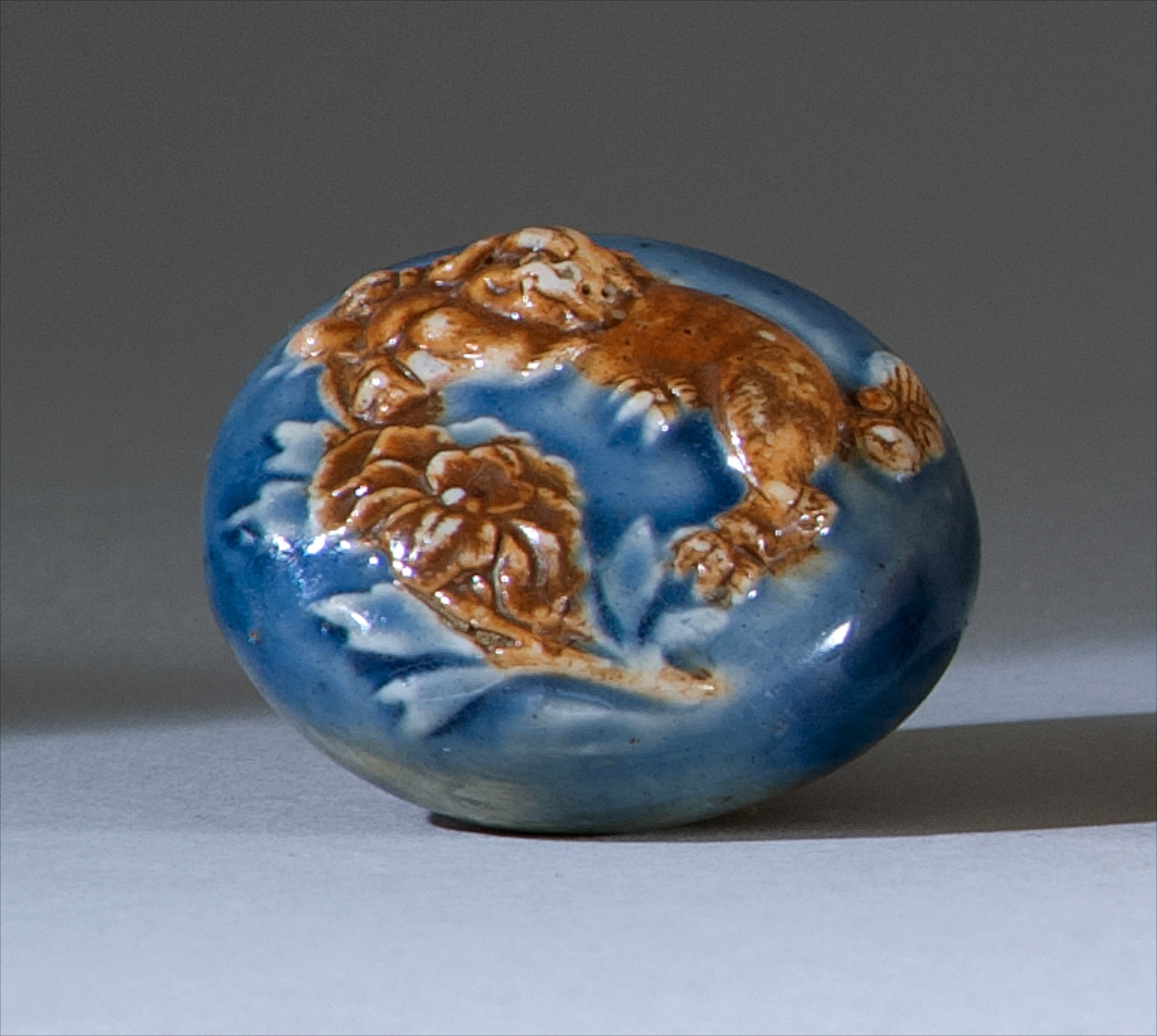 Appraisal: PORCELAIN NETSUKE th CenturyIn circular form with brown shishi and