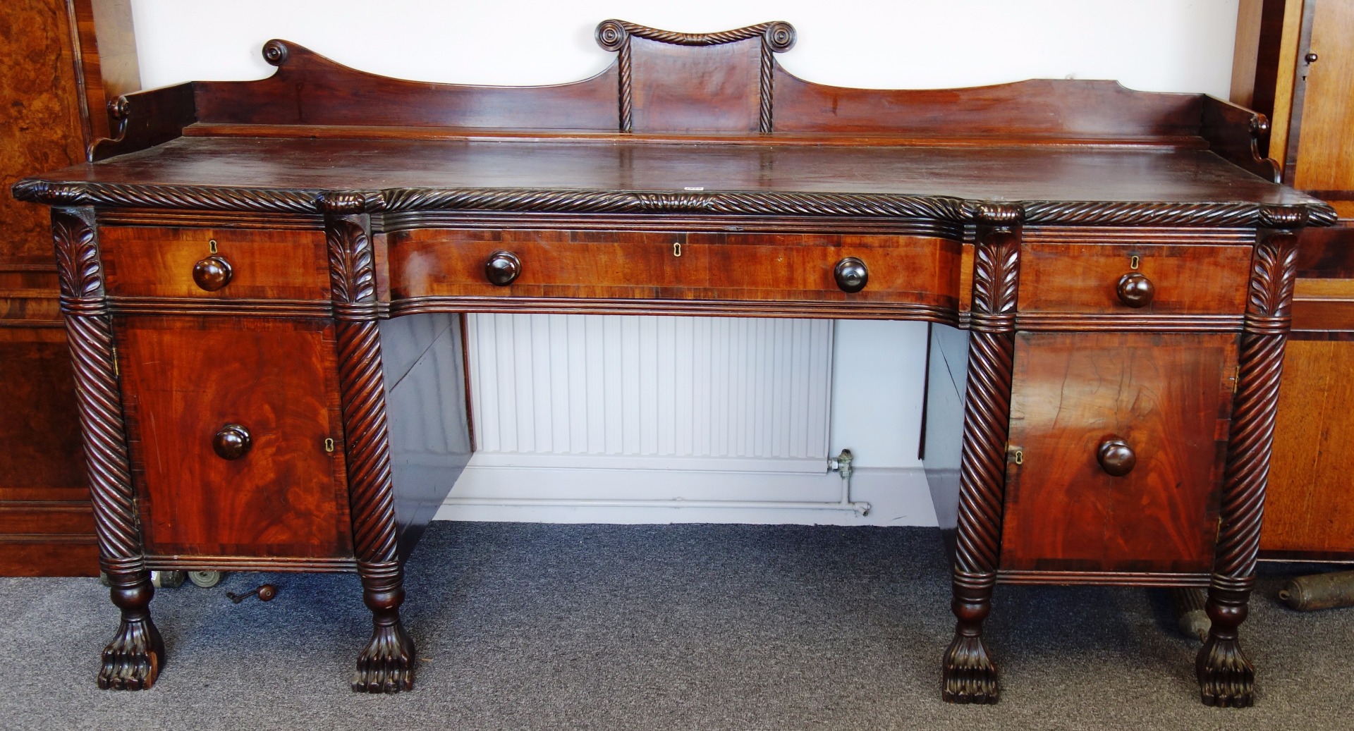 Appraisal: An early th century crossbanded mahogany inverted breakfront pedestal sideboard